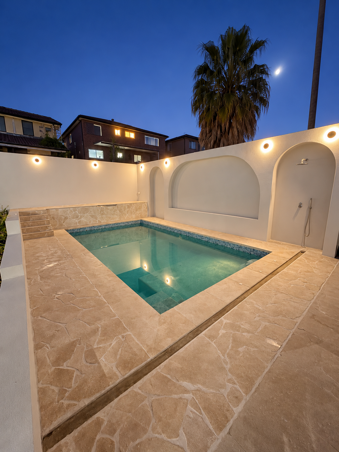 Finished swimming pool with stone paving and illuminated arched walls